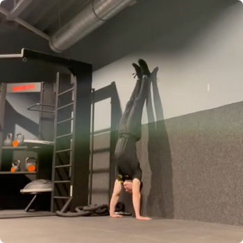 Wall assisted handstand kick ups